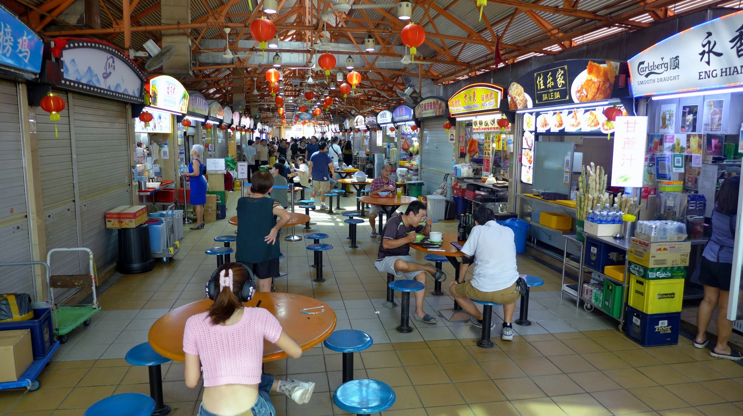 Зал Maxwell Food Centre в Чайнатауне. Это реальная городская остановка за едой; меню, цены и открытые прилавки меняются.
